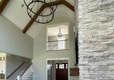 Living room with vaulted ceiling, stone fireplace, and chandelier light fixture