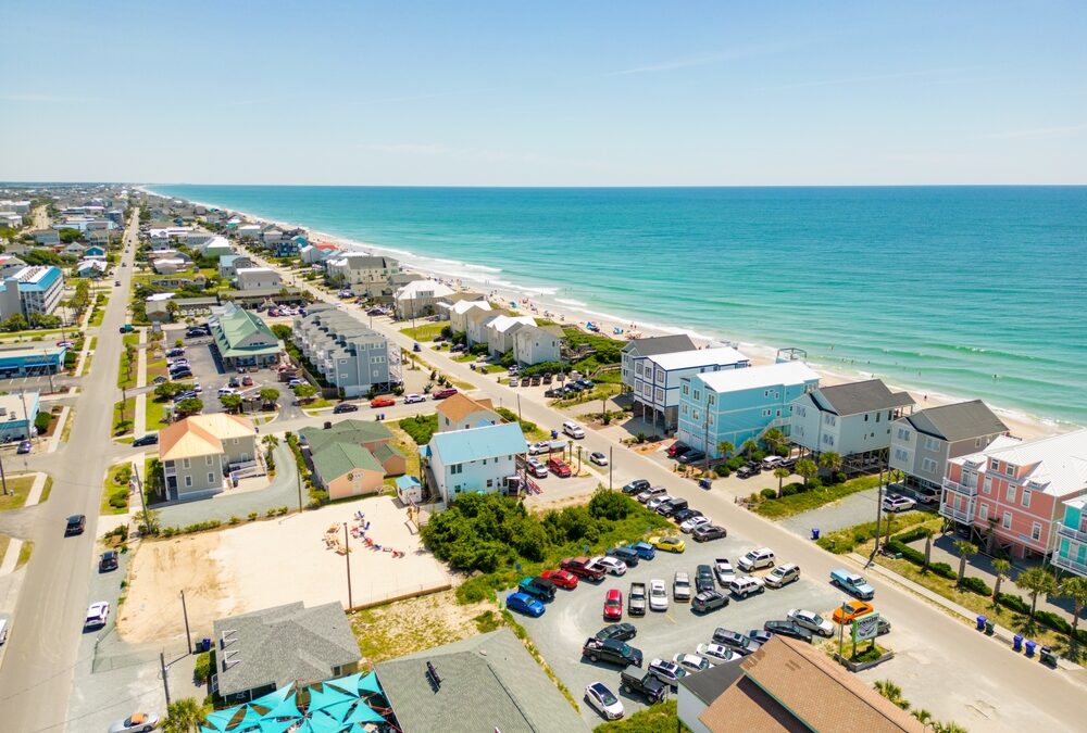 Aerial view of a coastal beach town with beachfront homes and turquoise ocean water