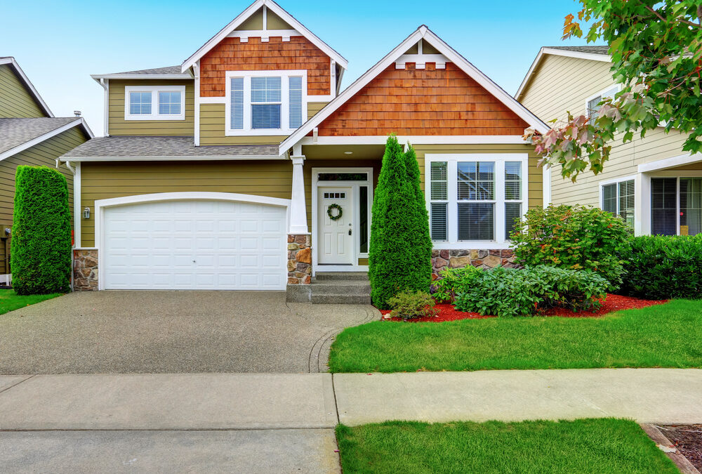 Craftsman-style home exterior with olive green siding, wood shingle gables, and a two-car garage